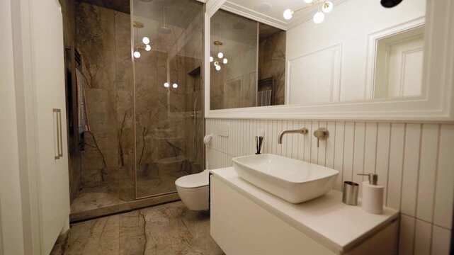 Elegant modern bathroom with large stone-tile shower area, wall-mounted toilet, minimalist white vanity, oversized mirror and warm ambient lighting
