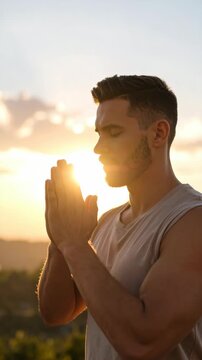 Young adult man with beard meditating outdoors at sunset with hands clasped in prayer, looking for spiritual harmony and tranquility.