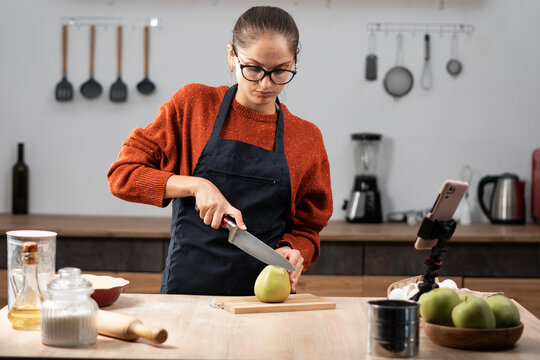 Food Blogging. woman baking on camera in kitchen, recording video for social media on smartphone cooking apple pie - Powered by Adobe
