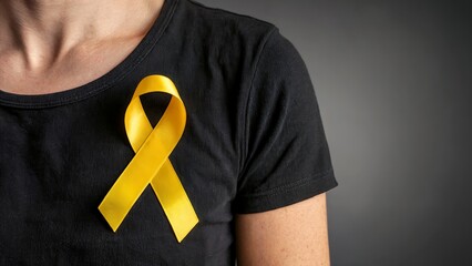 Close-up of a Yellow Awareness Ribbon Pinned to a Black T-shirt