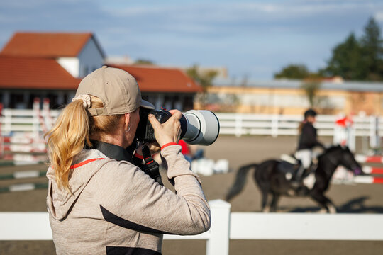 Sports photographer with camera and telephoto lens capturing equestrian show jumping. Photography themes