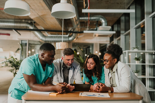 Diverse medical team collaborating on digital tablet in hospital