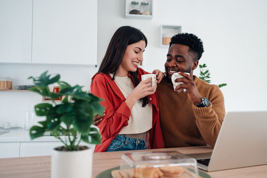 Diverse couple drinking coffee together in kitchen