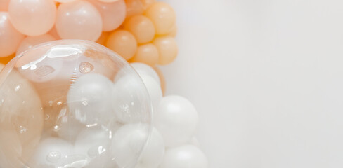 Soft pastel balloon decoration with white, peach and transparent balloons forming an elegant party backdrop on a clean white background.