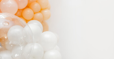 Soft pastel balloon decoration with white, peach and transparent balloons forming an elegant party backdrop on a clean white background.