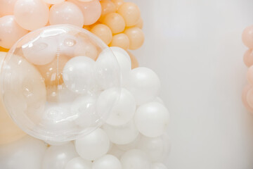 Minimal pastel balloon decoration with white, peach and transparent balloons on a clean white...