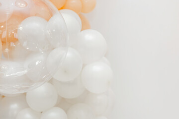 Soft pastel balloon decoration with white, peach and transparent balloons forming an elegant party backdrop on a clean white background.