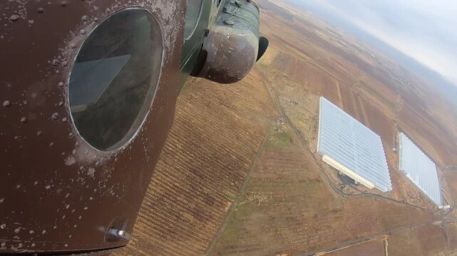 Wide-angle view from a fast-moving aircraft shows the brown fuselage and the blurred, dry ground below, emphasizing speed and low altitude travel over desolate terrain.