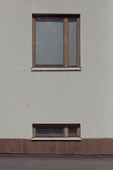 Wood framed wall window and basement window on stone building exterior, Alppila, Helsinki, Finland.