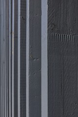 Close-up photograph of a board and batten style wall or fence with vertical planks painted a uniform gray color, Pitkäsilta, Helsinki, Finland.