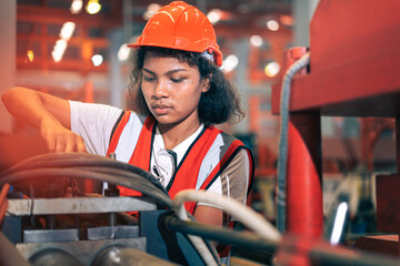 Professional Black African female factory engineer/worker/technician operate machinery in modern industrial plant. She wear safety helmet,vest show focus,skill in repair maintenance production process