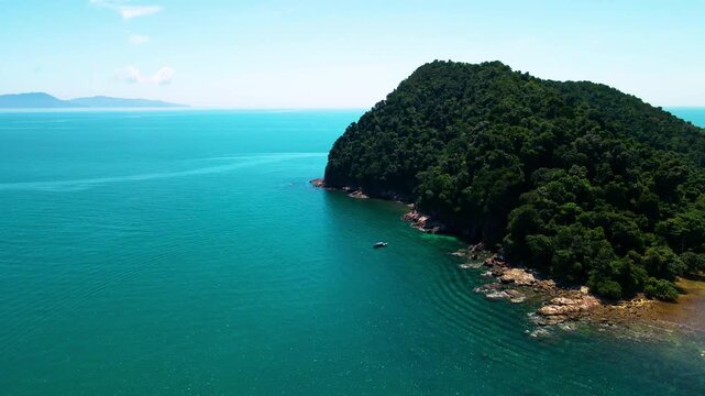 Aerial view of a small tropical island located just off the coast of Pantai Bukit Keluang in Besut, Terengganu. The island is covered in dense green forest and surrounded by vibrant turquoise waters.