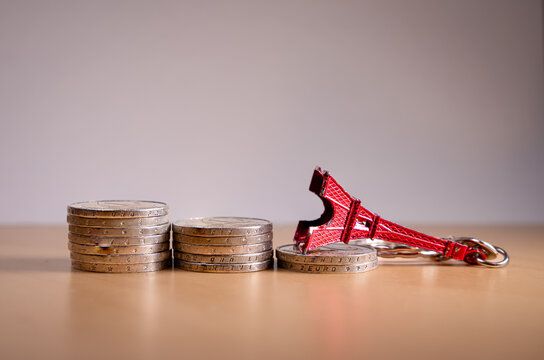 Eiffel Tower souvenir falling near euro coins symbolizing France economic crisis