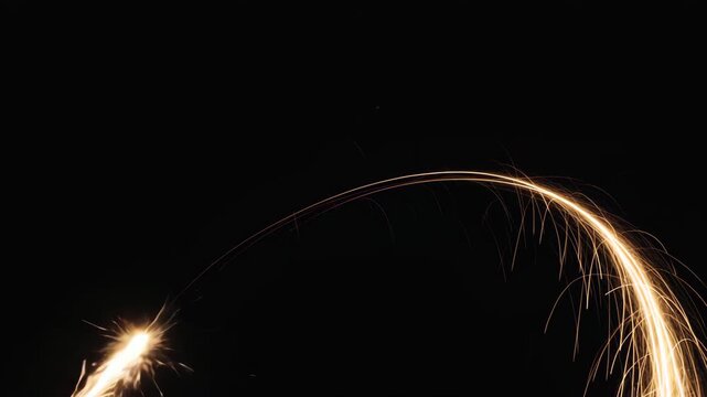 Golden light streaks arc across black background with glowing sparks flying outwards abstract 4K Ai HD high quality video.	
