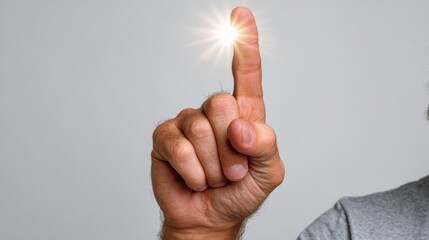 A close-up of a male hand, Caucasian, pointing upwards with a glowing light at the fingertip, symbolizing inspiration or a bright idea.