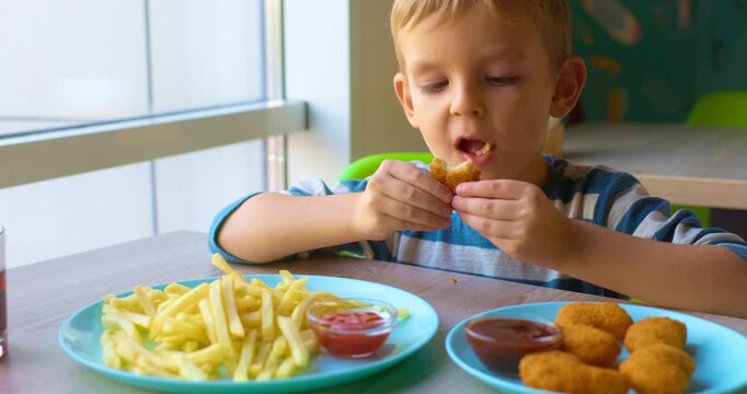 Child Enjoys Chicken Nuggets and Fries at a Table in a Cafe
