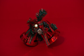 Christmas bells with a festive design displayed against a vibrant red background, featuring shiny metallic details and holiday ribbons. Traditional seasonal decoration symbolising joy and celebration