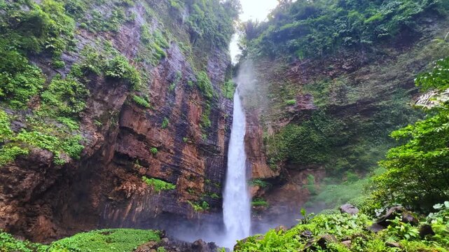 Koban Kapas Biru is a waterfall in the tropical jungles of East Java, descending from a high cliff into a lush green canyon surrounded by tropical forests with vibrant vegetation.Lumajang River. 4К