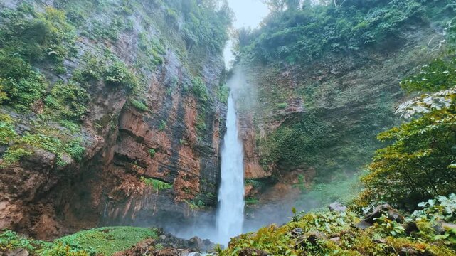 Koban Kapas Biru is a waterfall in the tropical jungles of East Java, descending from a high cliff into a lush green canyon surrounded by tropical forests with vibrant vegetation.Lumajang River. 4К	