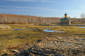 A picturesque rural mosque in Bashkortostan during early spring, surrounded by melting snow and budding trees. Soft natural light highlights the architecture and serene countryside setting.