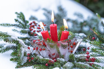 Weihnachtsdekoration mit roten Kerzen und Eislaterne im Garten	
