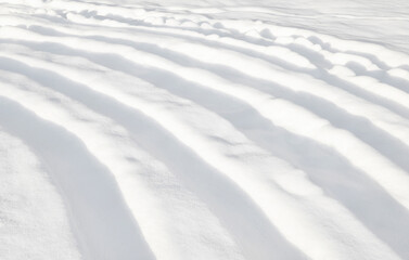 Winter background. An abstract pattern of deep curved furrows in the snow.