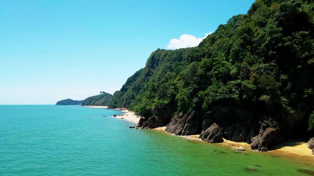 Aerial view of Pantai Bukit Keluang, Besut, Terengganu, showing turquoise waters, coastal cliffs, and clear sunny skies along the scenic shoreline.