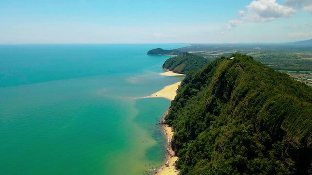 Aerial view of Pantai Bukit Keluang, Besut, Terengganu, showing turquoise waters, coastal cliffs, and clear sunny skies along the scenic shoreline.