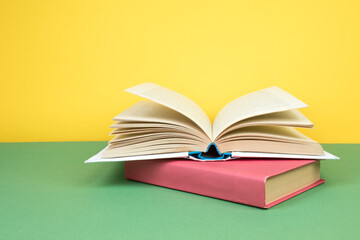 Books stacking. Open hardback books on wooden table and green background. Back to school. Copy space for ad text.