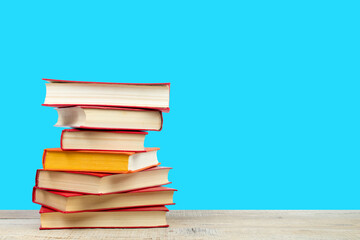 Composition with hardback books on wooden deck table and blue background. Books stacking. Back to school. Copy Space. Education background.