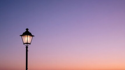 Elegant lowangle view of ornate lamp post illuminated under vibrant orange to violet gradient sky with spacious copy area