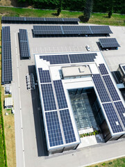 Fototapeta premium Aerial view of building with solar panels on a roof and parking space with solar canopies