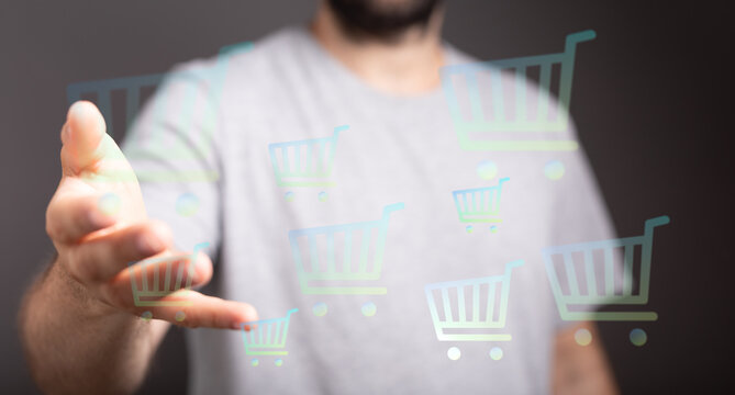 A man's hand reaches towards floating shopping cart icons, representing online shopping, sales and digital commerce. Perfect for e-commerce or r