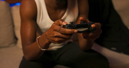 A relaxed male figure sits on a sofa at home, enjoying virtual entertainment with a console...
