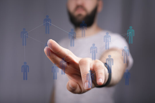 Close-up of a hand touching a digital networking concept with connected people icons on grey background. - Powered by Adobe