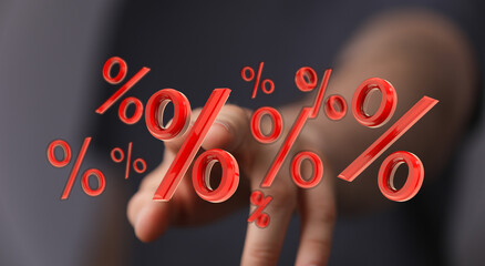 Close-up of a hand pointing at floating percentage symbols. Concept representing finance,...