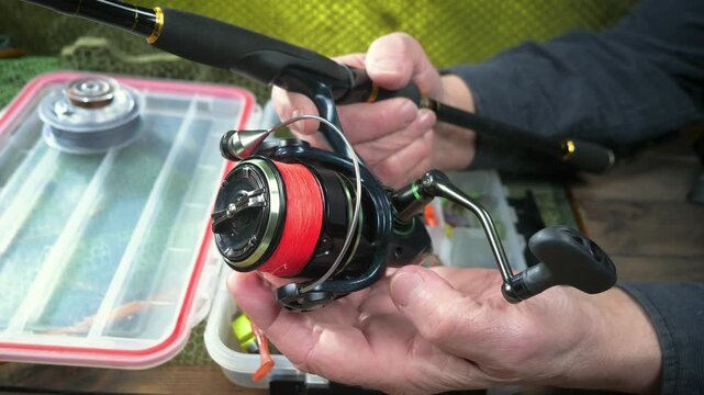 A fisherman assembles and checks his tackle before fishing. Close-up of his hands.