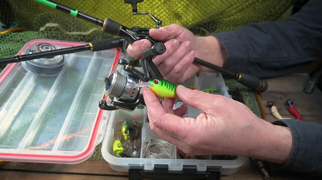 A fisherman assembles and checks his tackle before fishing. Close-up of his hands.