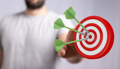 Close-up of a man holding a dart board and darts with all three hitting the bullseye representing a...