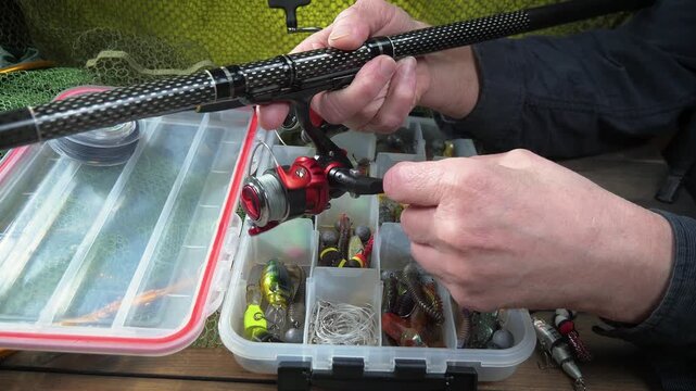 A fisherman assembles and checks his tackle before fishing. Close-up of his hands.