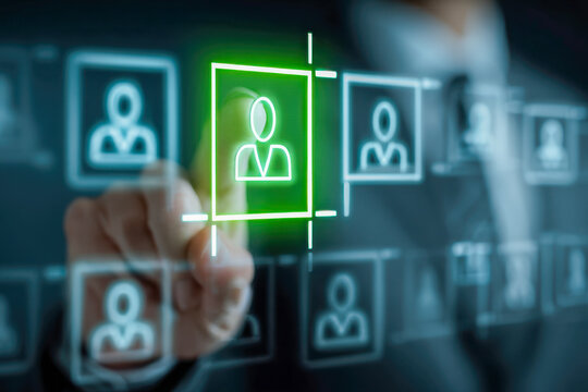 Business professional selecting a glowing green user icon on transparent digital interface representing recruitment or team management process online