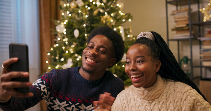 Cheerful sister and brother unpack gifts and have video call with parents. They show decorated Christmas tree and living room and share their plans for the holidays. - Powered by Adobe