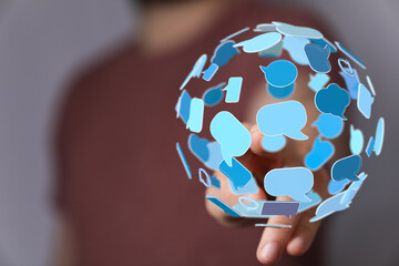 Abstract image of a hand holding a sphere made of speech bubbles, conveying concepts of digital...