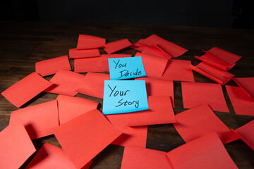 Blue sticky notes on a pile of red sticky notes on a dark wood surface with text reading You Decide...