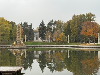 Fototapeta premium Autumn park lake with trees reflecting in water in tranquil setting, suitable for background