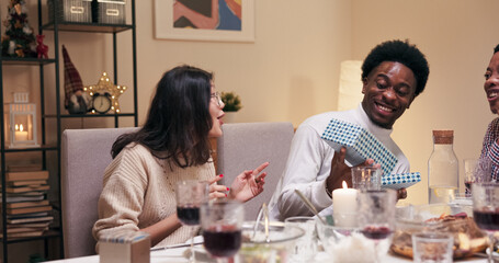 The multi-ethnic student, wearing a white golf shirt, unpacked the box of a gift from a girl with black long hair. He was happy and showed the surprise to his friends, who rejoice, communicate, and