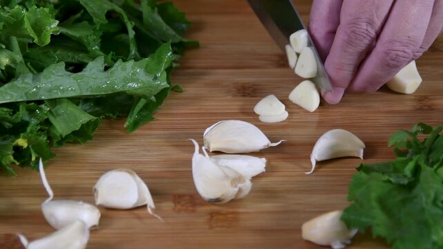 Man cut and chopping garlic on wooden board for cooking