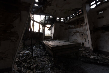 Derelict room with billiard table and collapsed roof in a ruined interior
