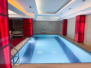 An indoor pool with blue water, red neon lighting and a modern interior