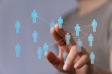 Hand touching digital network human icons, representing social connections, technology, communication, and team